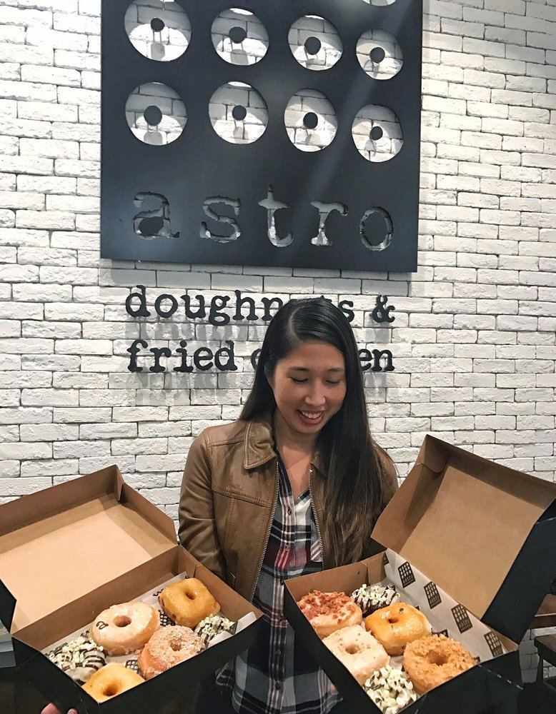 A customer photographed on The Printing House Yelp page, holding two boxes at Astro Doughnuts