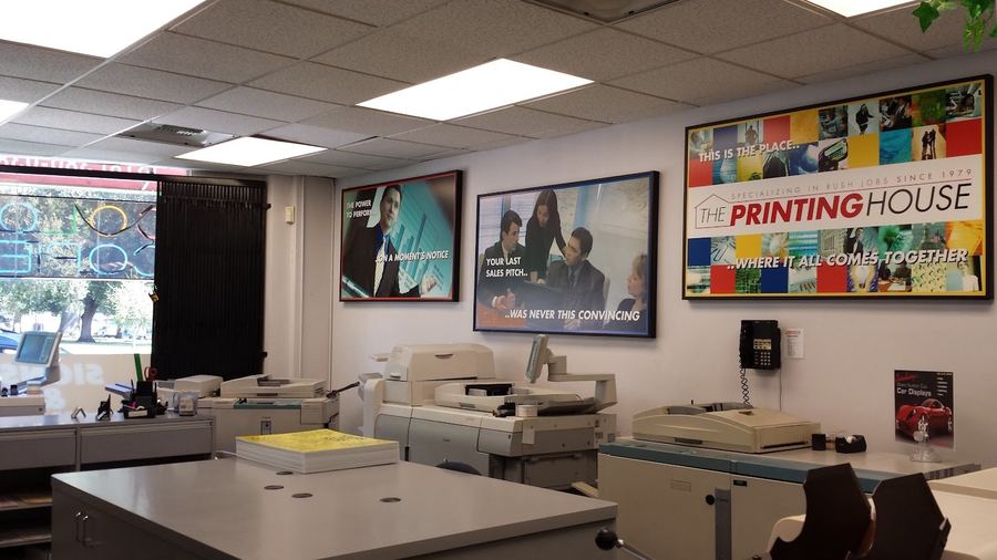 The front counter at The Printing House, the shop's own framed work on the wall and the digital presses behind it